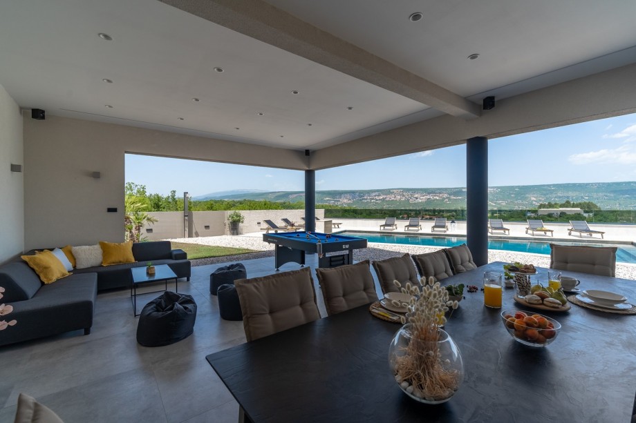 Covered area (77sqm) with an outdoor kitchen, a traditional barbecue (woods and charcoal), a huge flat screen TV with surround speakers, a dining table for 12 people