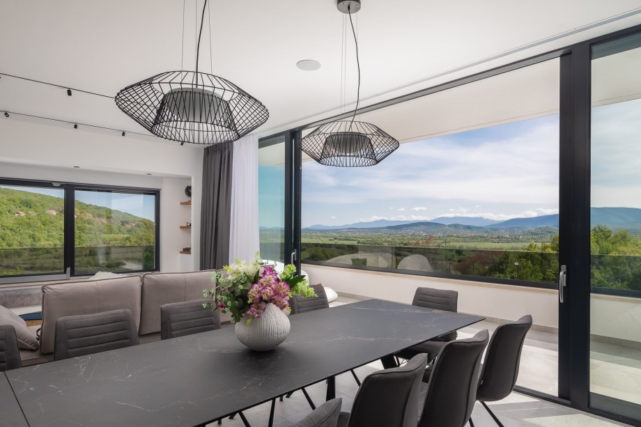 A spacious dining area, and a living room with a flat-screen TV and a balcony overviewing the valley and pool area