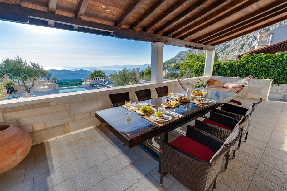 Spacious, covered terrace with outdoor dining area between pool and living area