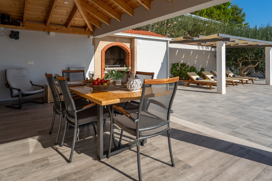 Covered outdoor dining area for 6 people with TV and a barbecue