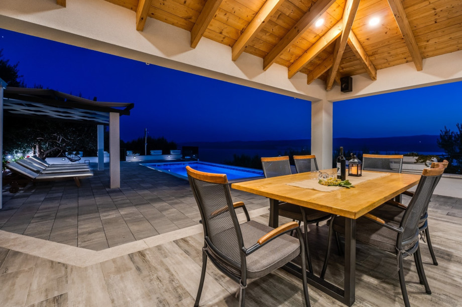 Outdoor dining area, grill and pool area in the evening