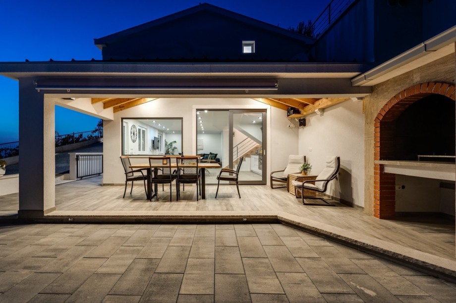 Outdoor dining area, grill and pool area in the evening