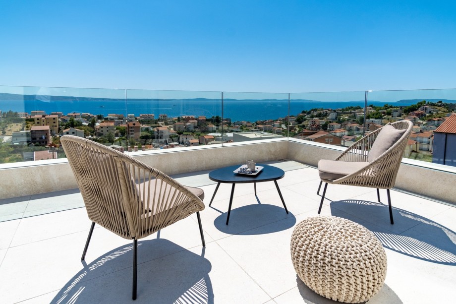 A spacious terrace with outdoor furniture offers amazing sea and pool views