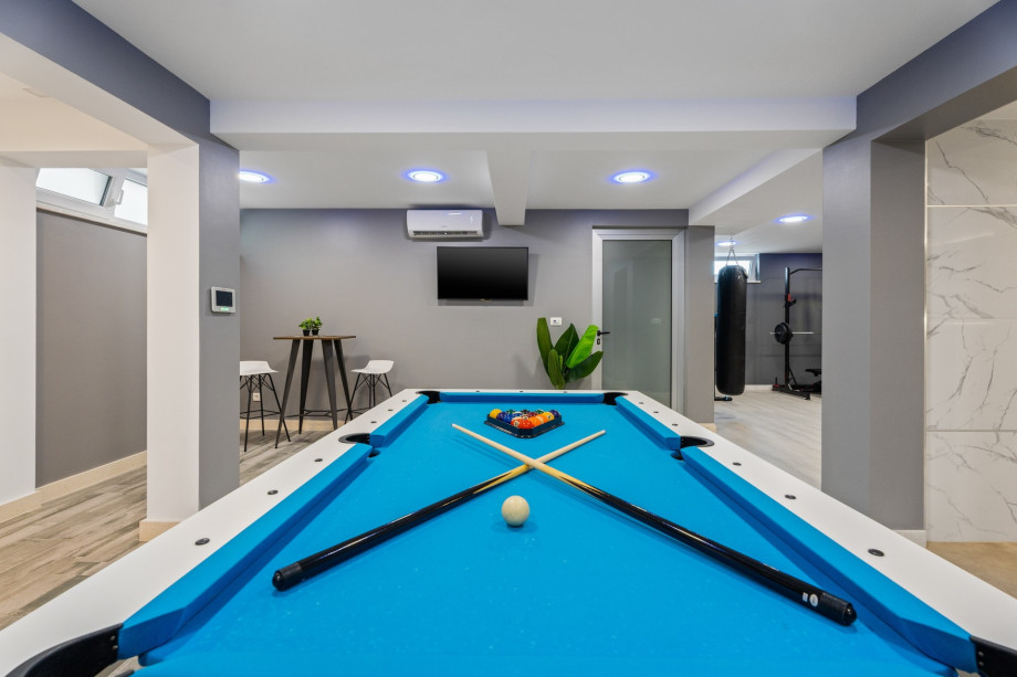 There is a billiard, a bar, a sofa with TV, Netflix, and a PS4 for young members
