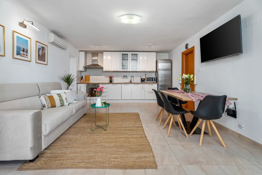 The living area (1st floor) offers a sofa that can open into a sofa bed, a dining table for 6 people, a TV, and an Air-conditioner.