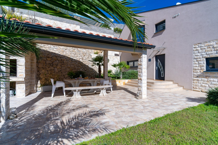 Outdoor dining area with furniture next to the grill, open sea view