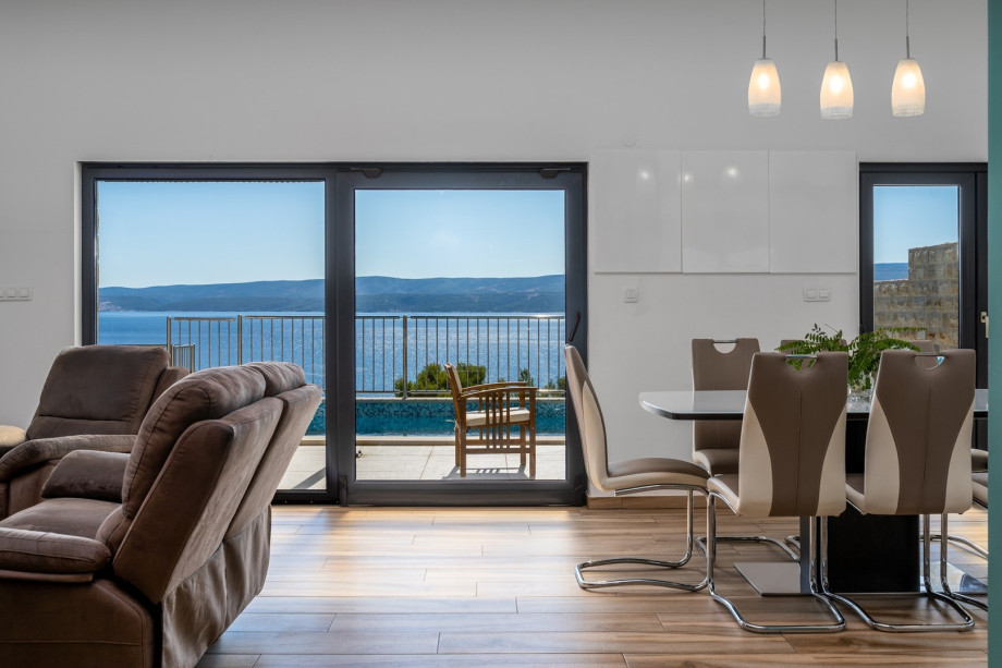 The living area has glass walls toward the pool and outdoor area