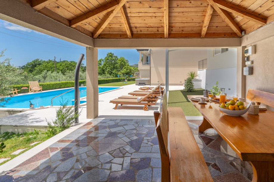 Comfortable and covered outdoor dining area with a traditional barbecue