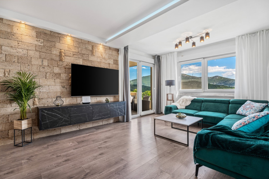 Villa BEYBE interior offers an Airconditioned Living and dining area with TV, and an exit to the outdoor lounge corner with a view of a pool area