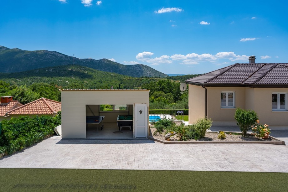 From the parking side is a covered area with billiards (pool table) and table tennis