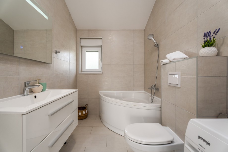 Family bathroom with a bathtub and washing machine