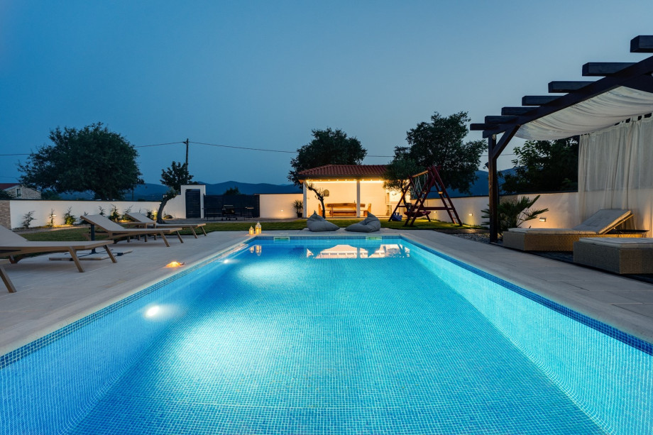 An outdoor area offers a shower, a children's playground with a slide, swing, seesaw, and a badminton net.