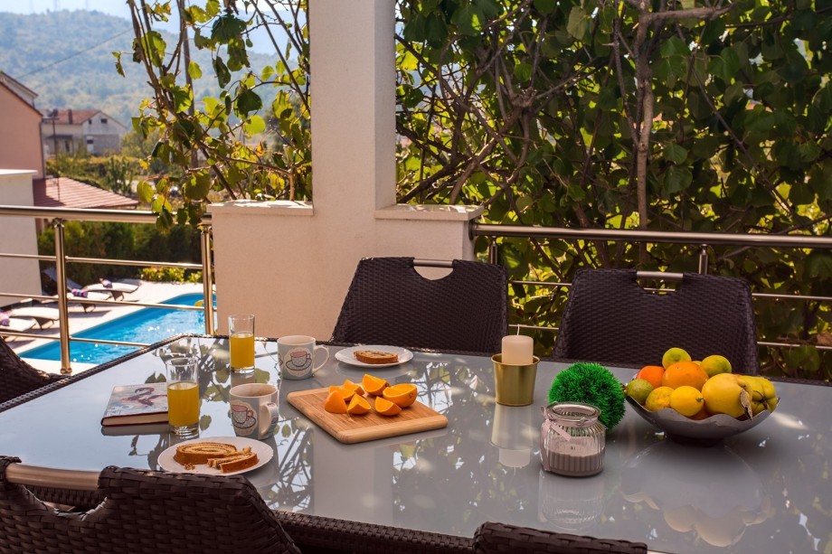Outdoor dining area on spacious terrace with pool view
