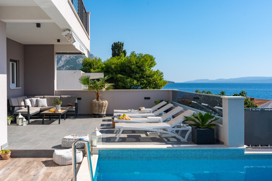 A terrace with lounge sitting, 6 deck chairs, and a private swimming pool