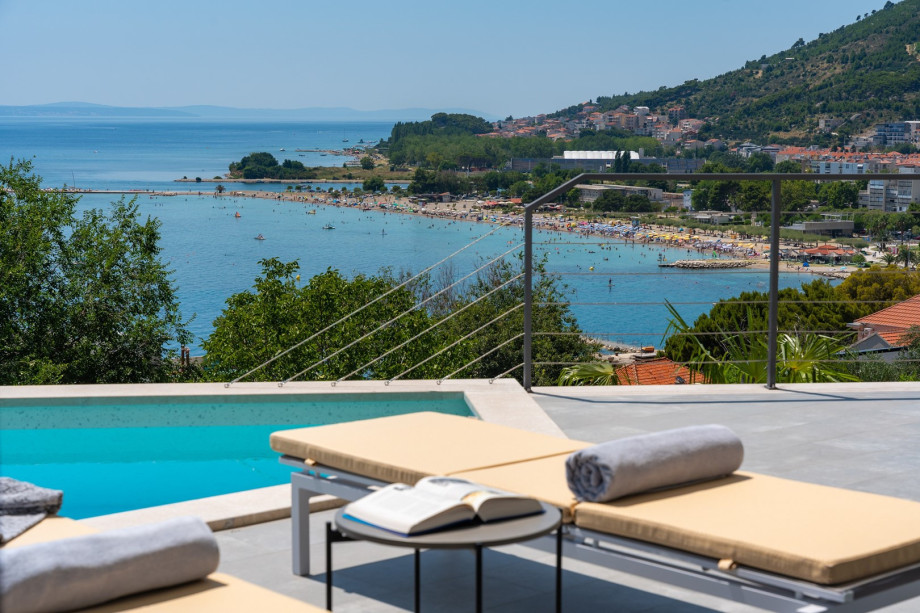 a sun deck area with 6 decks chairs overviewing town Omiš, sea and mountains