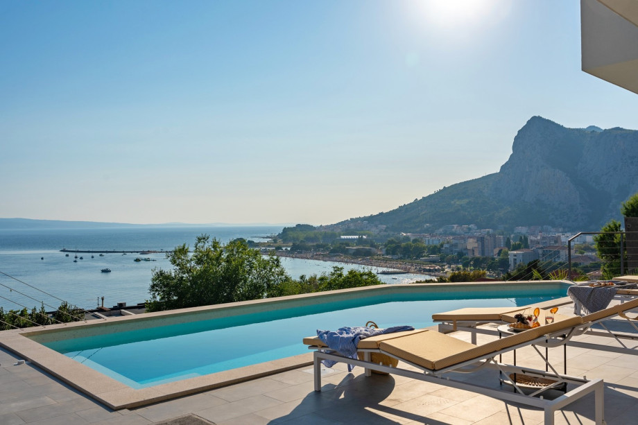a sun deck area with 6 decks chairs overviewing town Omiš, sea and mountains