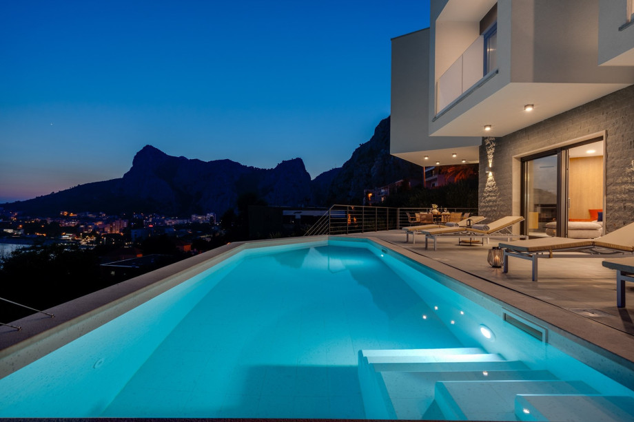 a sun deck area at night, with 6 decks chairs overviewing town Omiš, sea and mountains