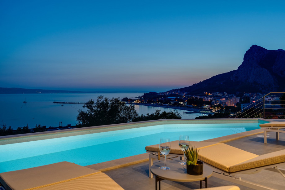 a sun deck area at night, with 6 decks chairs overviewing town Omiš, sea and mountains