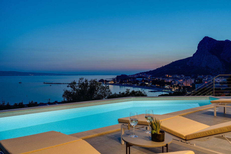 a sun deck area at night, with 6 decks chairs overviewing town Omiš, sea and mountains