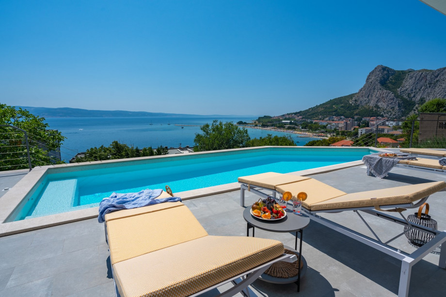 a sun deck area with 6 decks chairs overviewing town Omiš, sea and mountains