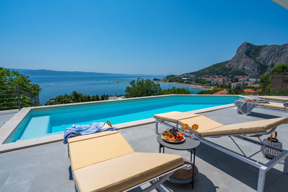 a sun deck area with 6 decks chairs overviewing town Omiš, sea and mountains