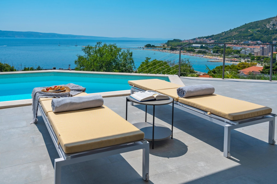 a sun deck area with 6 decks chairs overviewing town Omiš, sea and mountains