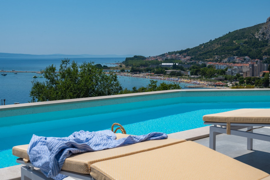 a sun deck area with 6 decks chairs overviewing town Omiš, sea and mountains
