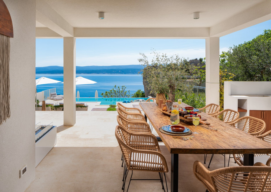 The covered outdoor area is a true oasis, complete with a private terrace and pool overlooking the azure sea