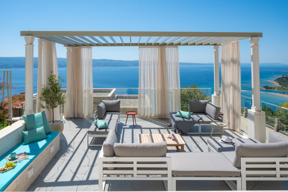 A cozy lounge area with curtains that offers a peaceful retreat to relax and appreciate the surrounding beauty and spectacular sunset and sea views