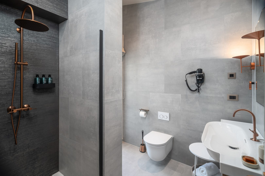 A bathroom with a shower and a door leading to the balcony that is shared by Bedroom 1 and Bedroom 2