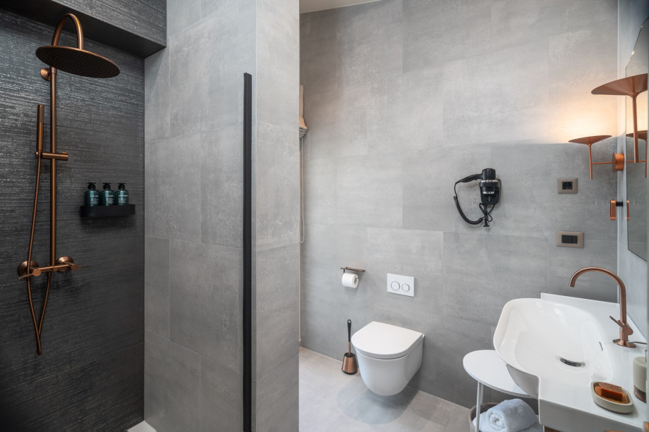 A bathroom with a shower and a door leading to the balcony that is shared by Bedroom 1 and Bedroom 2