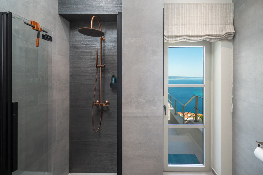 A bathroom with a shower and a door leading to the balcony that is shared by Bedroom 1 and Bedroom 2
