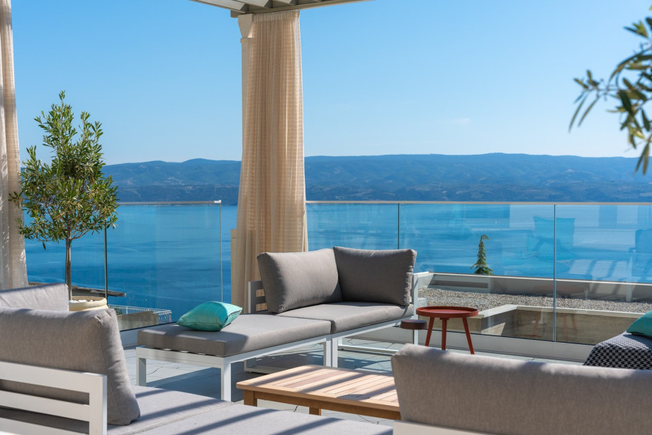 A cozy lounge area with curtains that offers a peaceful retreat to relax and appreciate the surrounding beauty and spectacular sunset and sea views