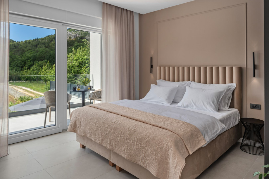 Bedroom NO1 with a king-size bed, A/C, TV, balcony overlooking the pool and surrounding landscape, and ensuite bathroom with a bathtub.