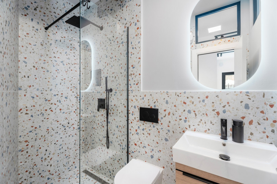 A Family bathroom with a shower. There is also a washing machine and ironing amentines in the hallway.