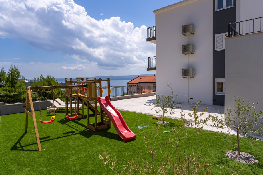 Large sundeck area features an artificial grassplot, a wooden kids house with a slide and some extras for your youngest guests