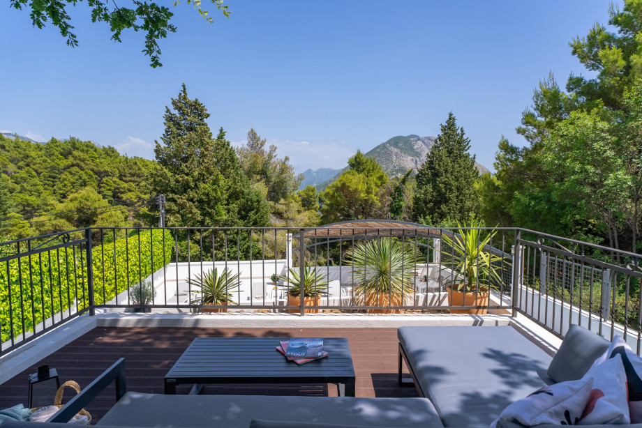 Lounge corner above sauna overviewing the pool and green scenery