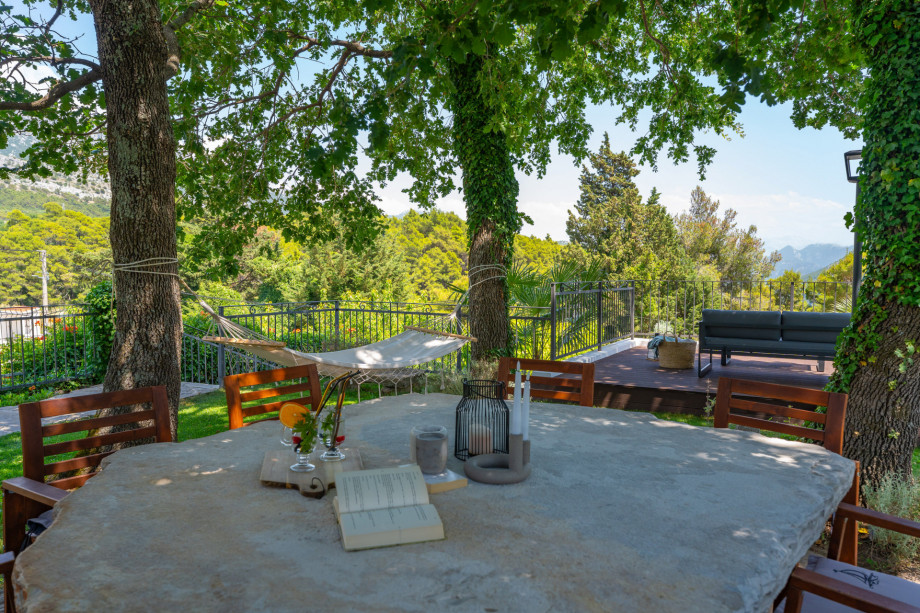 Unique stone table under the oak trees overviewing the pool and mountains