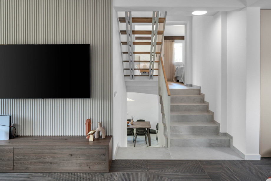Flat screen TV, PlayStation 5, fire place and staircase toward kitchen and bedrooms