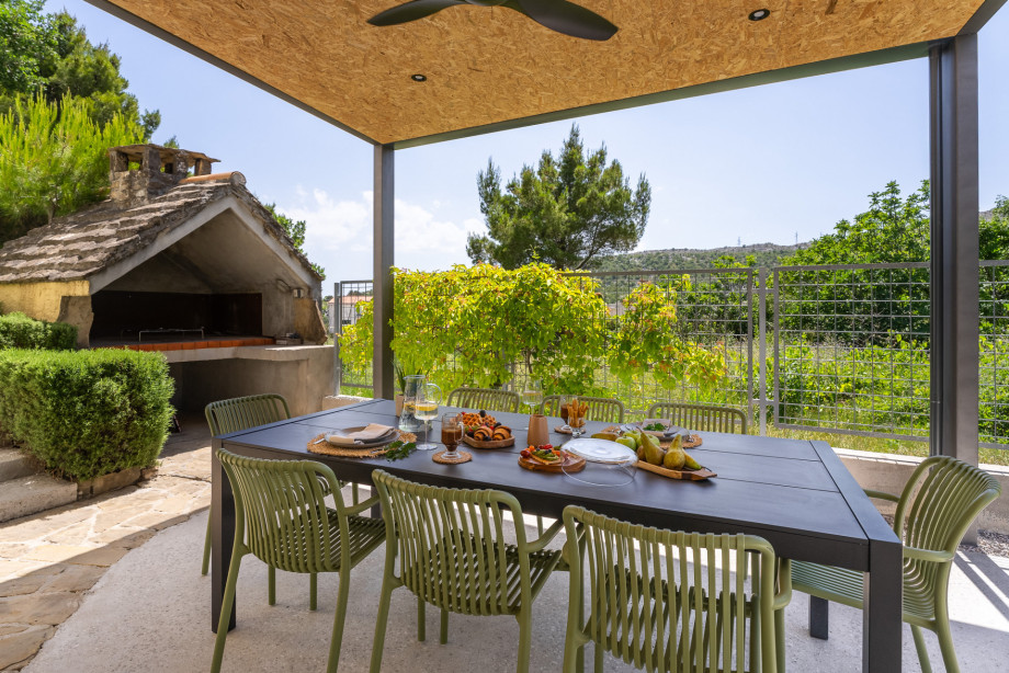 Fenced outdoor covered dining area with a barbecue and grassplot