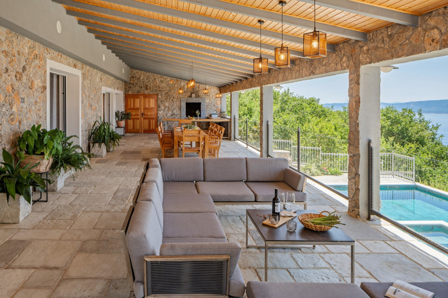 Large covered patio complete with a kitchen island, grill, outdoor dining set, and lounge