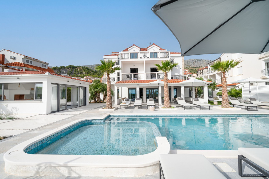 The outdoors offers a private 54m2 heated swimming pool (12m x 4,5m) with lounge seats and a fire pit next to it, a sun deck area with 14 deck chairs and a summer kitchen