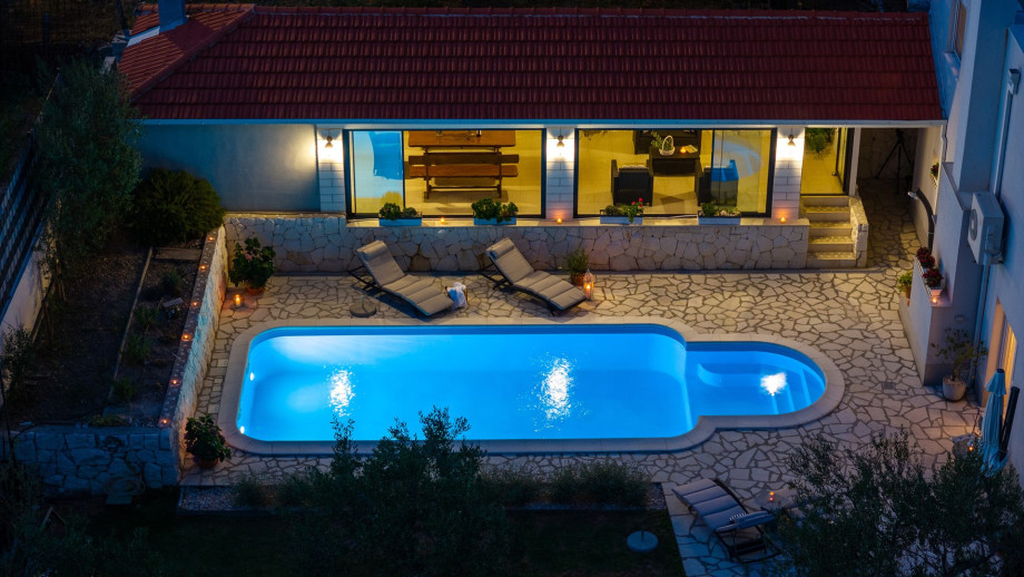 Private pool with covered dining and sitting area at night