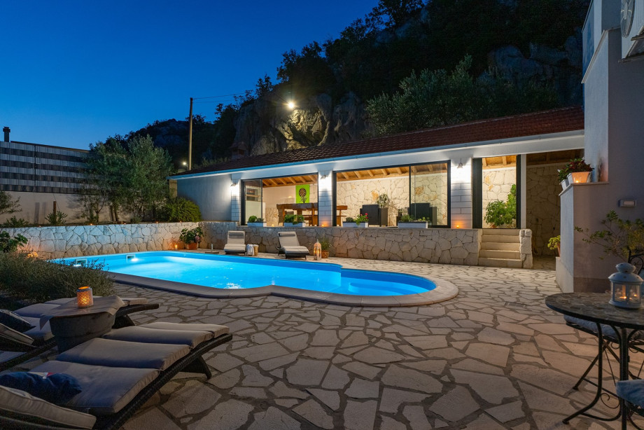 Sun deck area with 4 deck chairs and private pool, at night