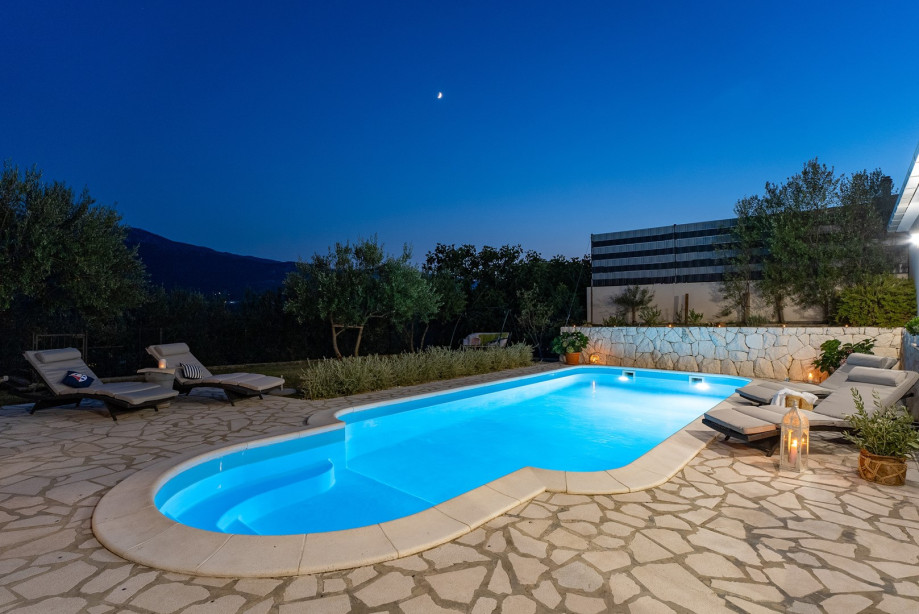 Sun deck area with 4 deck chairs and private pool, at night