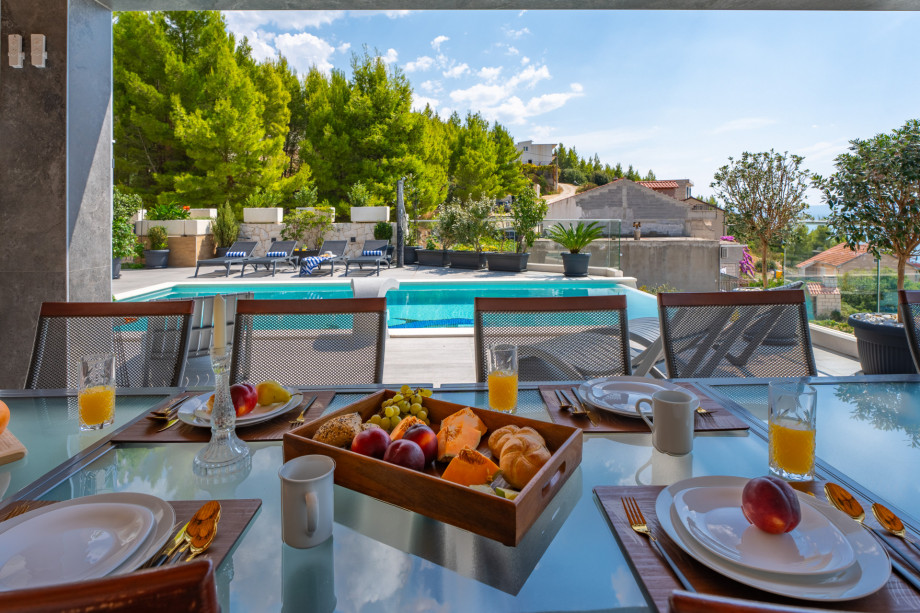 Outdoor dining area next to private heated pool and summer kitchen with grill