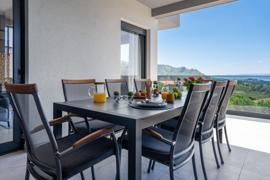 a covered outdoor dining area with a traditional barbecue (woods, charcoal) and a flat screen TV