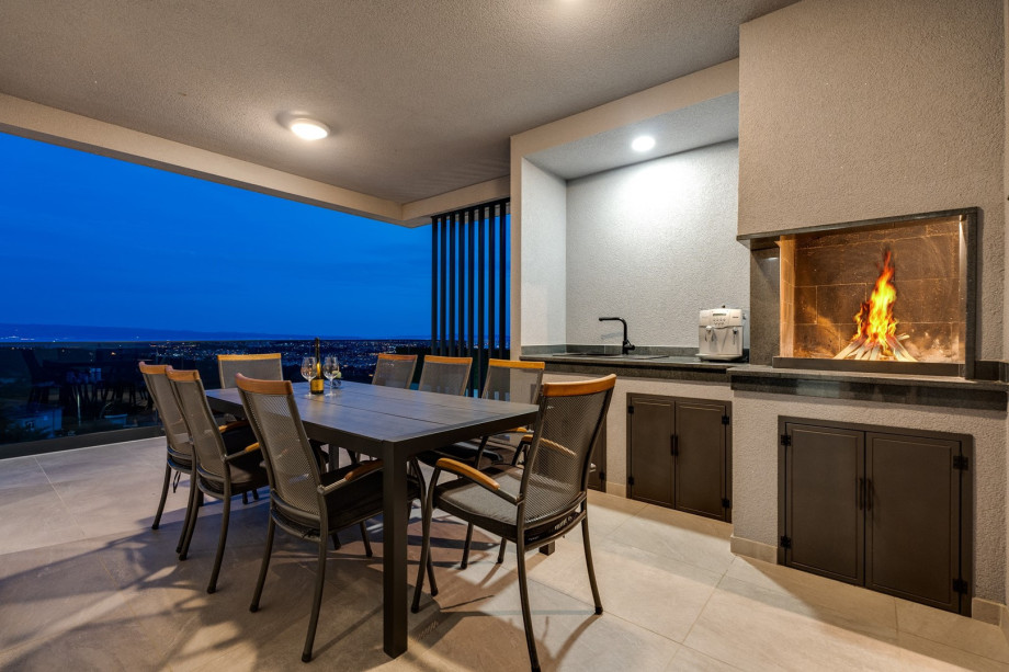 a covered outdoor dining area with a traditional barbecue (woods, charcoal) and a flat screen TV