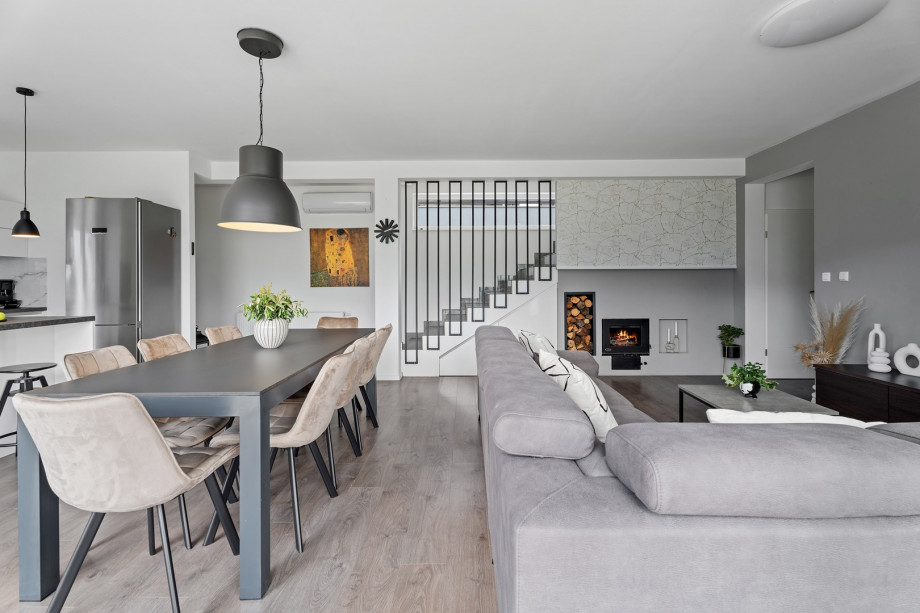 A  living room with sofa, flat-screen TV, a fireplace, a dining area for 8 people