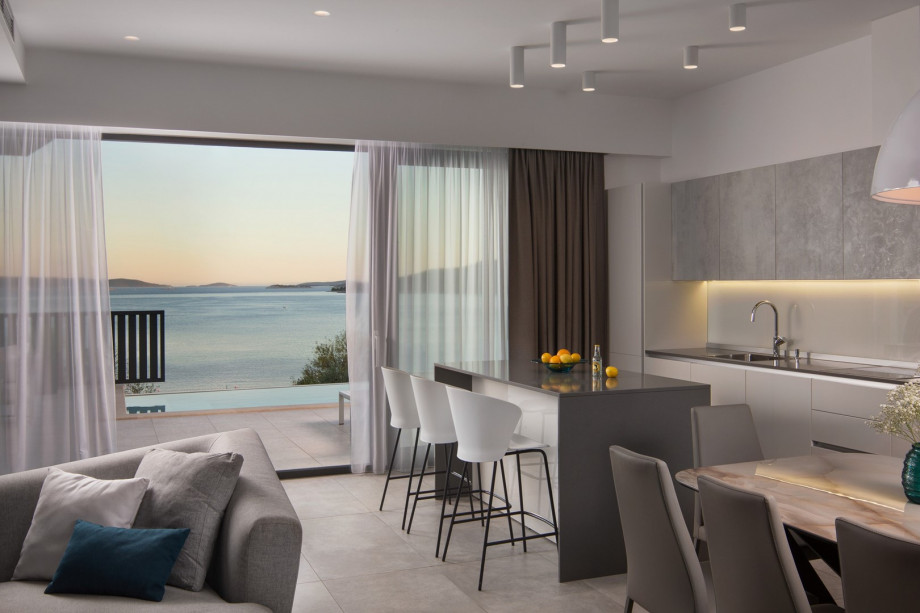 As you step inside, you are greeted by a seamless open-plan living, dining, and fully equipped kitchen area and a wonderful view of the sea